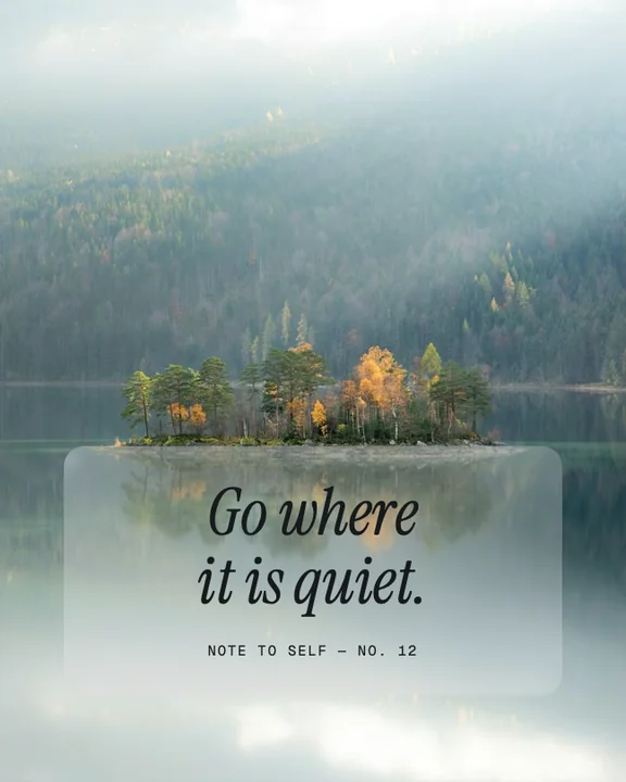A quote on a card of frosted glass over a misty lake with a small island of trees